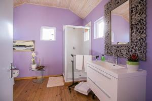 a purple bathroom with a sink and a mirror at Delightful db story loft with airconditioning in Hermanus