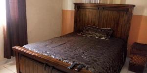 a bed with a wooden headboard in a room at Portmore Havens 1Bedroom EntireGuest House in Portmore