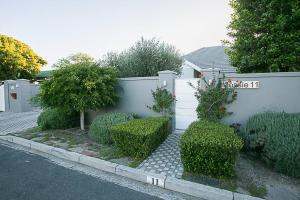 a garden with bushes and a white fence at Delightful db story loft with airconditioning in Hermanus