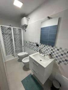 een badkamer met een wastafel, een toilet en een spiegel bij Casa vacanza Luén in Marigliano