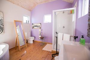 a purple bathroom with a toilet and a sink at Delightful db story loft with airconditioning in Hermanus