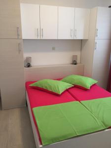 een bed met groene en rode lakens en witte kasten bij Apartments Dobrana in Novalja