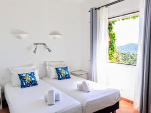 two beds in a white room with a window at Résidence Belvedere de Palombaggia in Porto-Vecchio