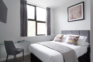 a bedroom with a bed and a chair and a window at Cotels at 7Zero1 Serviced Apartments - Modern Apartments, Superfast Broadband, Free Parking, Centrally Located in Milton Keynes