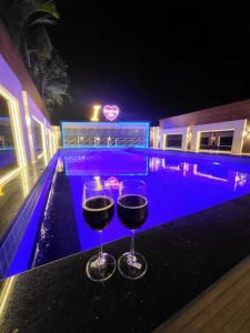 dos copas de vino sentadas en una mesa junto a una piscina en THE PERFECT STAYS: CHOUDHARY VILLA en Lonavala