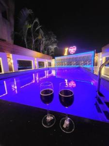 two wine glasses sitting next to a pool at night at THE PERFECT STAYS: CHOUDHARY VILLA in Lonavala