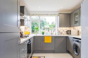 una cocina con armarios grises y una ventana en Stunning Place, close to Windsor & Heathrow & Private Parking en Burnham