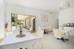 een eetkamer met witte tafels en witte stoelen bij Caza Beach Guesthouse in Durban