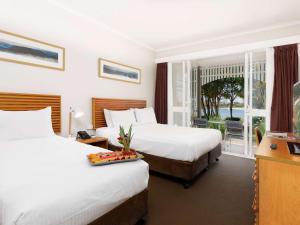 a hotel room with two beds and a balcony at Novotel Sunshine Coast Resort in Twin Waters
