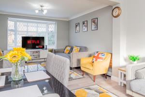 a living room with a couch and a tv at Stunning Place, close to Windsor & Heathrow & Private Parking in Burnham