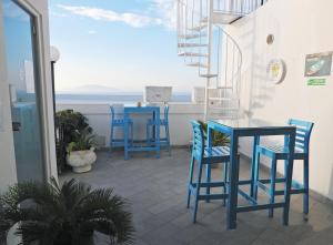 a balcony with blue chairs and a table with a view of the ocean at B&B La Danza del Mare in Anacapri