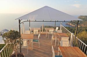 a deck with tables and chairs and a white umbrella at B&B La Danza del Mare in Anacapri