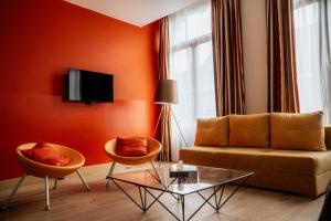 a living room with orange walls and a couch and chairs at Hotel d'Alcantara in Tournai