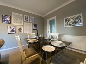 comedor con mesa de cristal y sillas en Stylish Apartment walk to train, 