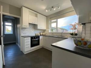 a kitchen with white cabinets and a black oven at Stylish Apartment walk to train 