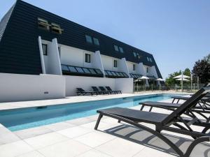 a swimming pool with chairs and a building at Ibis Styles Toulouse Labège in Labège
