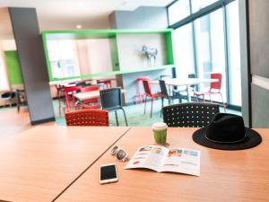 a hat on a table with a book and a cell phone at ibis Styles Moulins Centre in Moulins