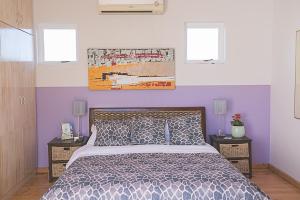 a bedroom with a bed with two night stands and two windows at Delightful db story loft with airconditioning in Hermanus
