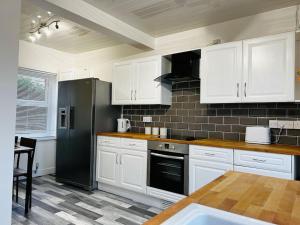 a kitchen with white cabinets and a black refrigerator at A Stones Throw From The Beach! in Vickerstown