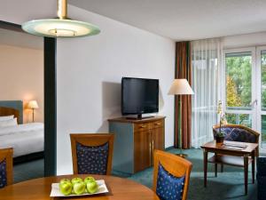 um quarto de hotel com uma mesa de jantar e uma televisão em Congress Hotel Weimar by Mercure em Veimar