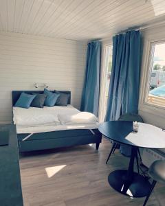1 dormitorio con 1 cama con cortinas azules y mesa en Frykenbadens Camping, en Kil