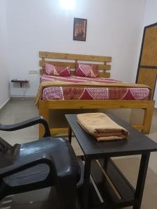 a bedroom with a bed and a table with a chair at Hotel Khushi Waves in Arpora