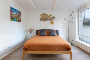 a bedroom with a bed with orange sheets and a window at La Maison de maître - centre historique - 3 rue henriette in Mulhouse