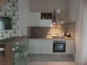 una cucina con armadi bianchi, tavolo e piano cottura di HappynessHouse_Locazione turistica a Trani