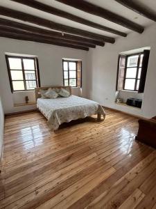 a bedroom with a bed and wooden floors and windows at Casa Campestre en Ibarra in Ibarra
