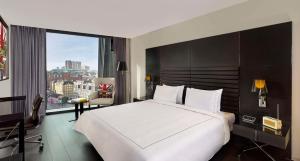 1 dormitorio con 1 cama blanca grande y ventana grande en art'otel London Hoxton, Powered by Radisson Hotels en Londres