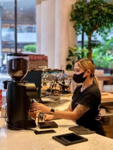 a woman wearing a face mask in front of a blender at Cozy Condo Apartment in Makati / Manila with mall, restaurants, groceries, pool, netflix, disney+ and more in Manila +42 photos