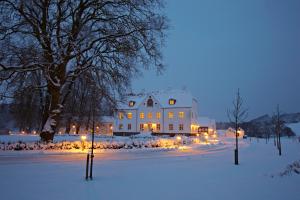 una grande casa bianca con le luci di Natale nella neve di Haraldskær Sinatur Hotel & Konference a Vejle