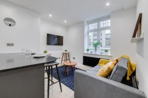 eine Küche und ein Wohnzimmer mit einem Sofa und einem Tisch in der Unterkunft Deluxe 1 Bed Flat - Shoreditch, Aldgate & The City of London in London