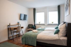 a bedroom with a bed and a desk and two windows at Volante Studio Bremen-Findorff in Bremen