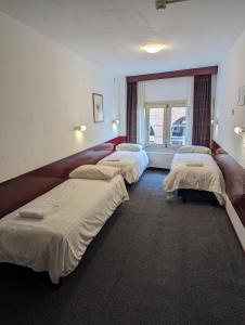 a row of beds in a room with a window at Budget Hotel Ben in Amsterdam