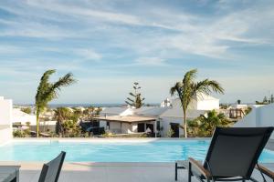a swimming pool with palm trees and a house at Villas Altos de Lanzarote in Playa Blanca