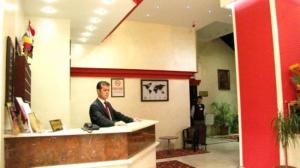 a man in a suit sitting at a counter at snowrose hotel in Şahinbey