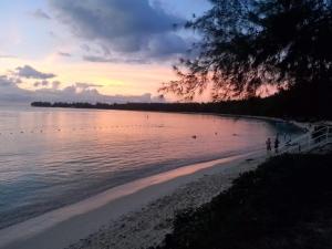 una spiaggia al tramonto con persone che camminano sulla sabbia di Le Petit Paradis a Trou d'Eau Douce