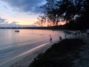 eine Gruppe von Menschen am Strand bei Sonnenuntergang in der Unterkunft Le Petit Paradis in Trou dʼ Eau Douce
