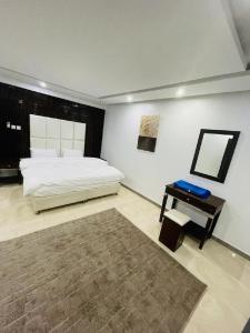 a bedroom with a bed and a table with a mirror at Desert Palm Aparthotel in Al Nairyah