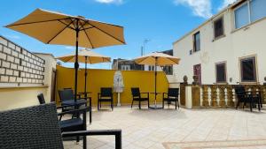 eine Terrasse mit Tischen, Stühlen und Sonnenschirmen in der Unterkunft Vittorio Emanuele Boutique Hotel in Sciacca
