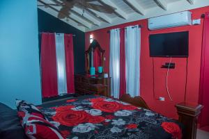 um quarto com uma cama com paredes vermelhas e uma televisão em PARADISE VILLA ONSITE PRIVATE POOL ONSITE PRIVATE GYm 2 PROPERTIES SLEEP 12 TO BOOK FOR MORE THAN 6 PLEASE CONTACT US em Ocho Rios