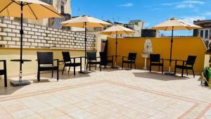 un patio con tavoli, sedie e ombrelloni di Vittorio Emanuele Boutique Hotel a Sciacca