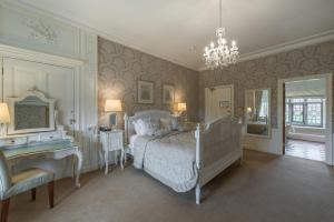 a bedroom with a bed and a desk and a chandelier at Rushton Hall Hotel and Spa in Kettering