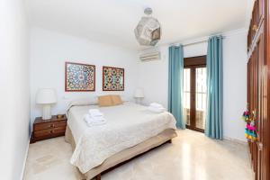 a white bedroom with a bed and blue curtains at CASA SAN MATIAS in Granada