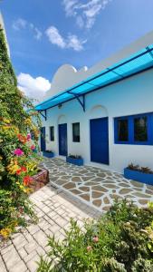biały budynek z niebieskimi drzwiami i kwiatami w obiekcie บ้านเพิงโฮมสเตย์ w mieście Ban Khuan Rai