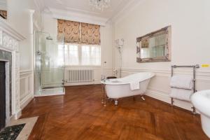 uma casa de banho branca com uma banheira e uma janela em Rushton Hall Hotel and Spa em Kettering