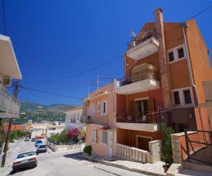 an apartment building with balconies and cars parked on a street at Artemis Central in Argostoli