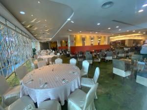 une salle à manger avec des tables et des chaises blanches dans l'établissement Kuching Imperial Suites Cozy Corner, à Kuching