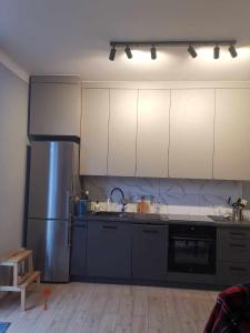 a kitchen with white cabinets and a stainless steel refrigerator at Apartament Słoneczny Olecko Centrum in Olecko